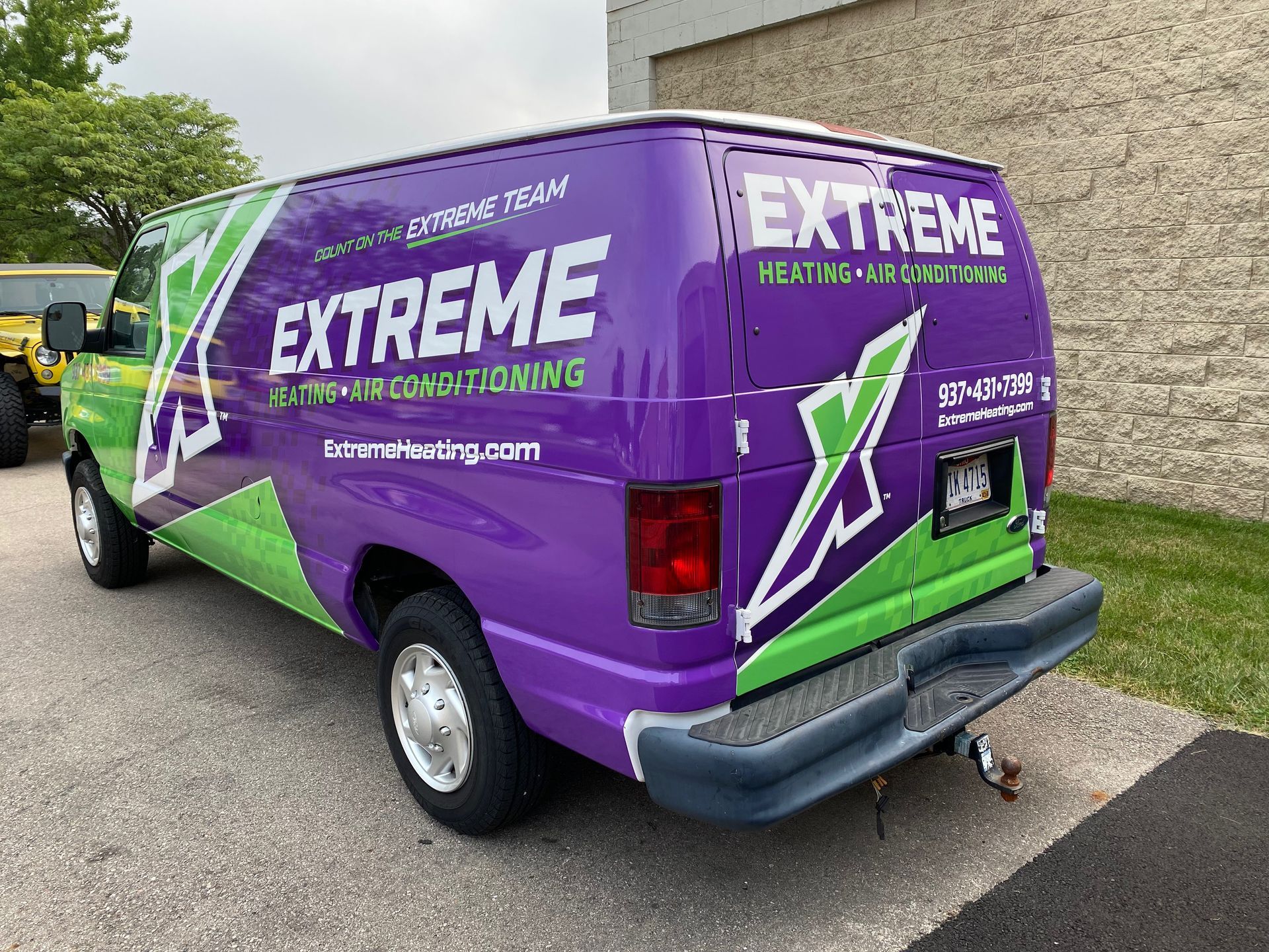 Purple and green Extreme Heating and Air Conditioning van parked outdoors.