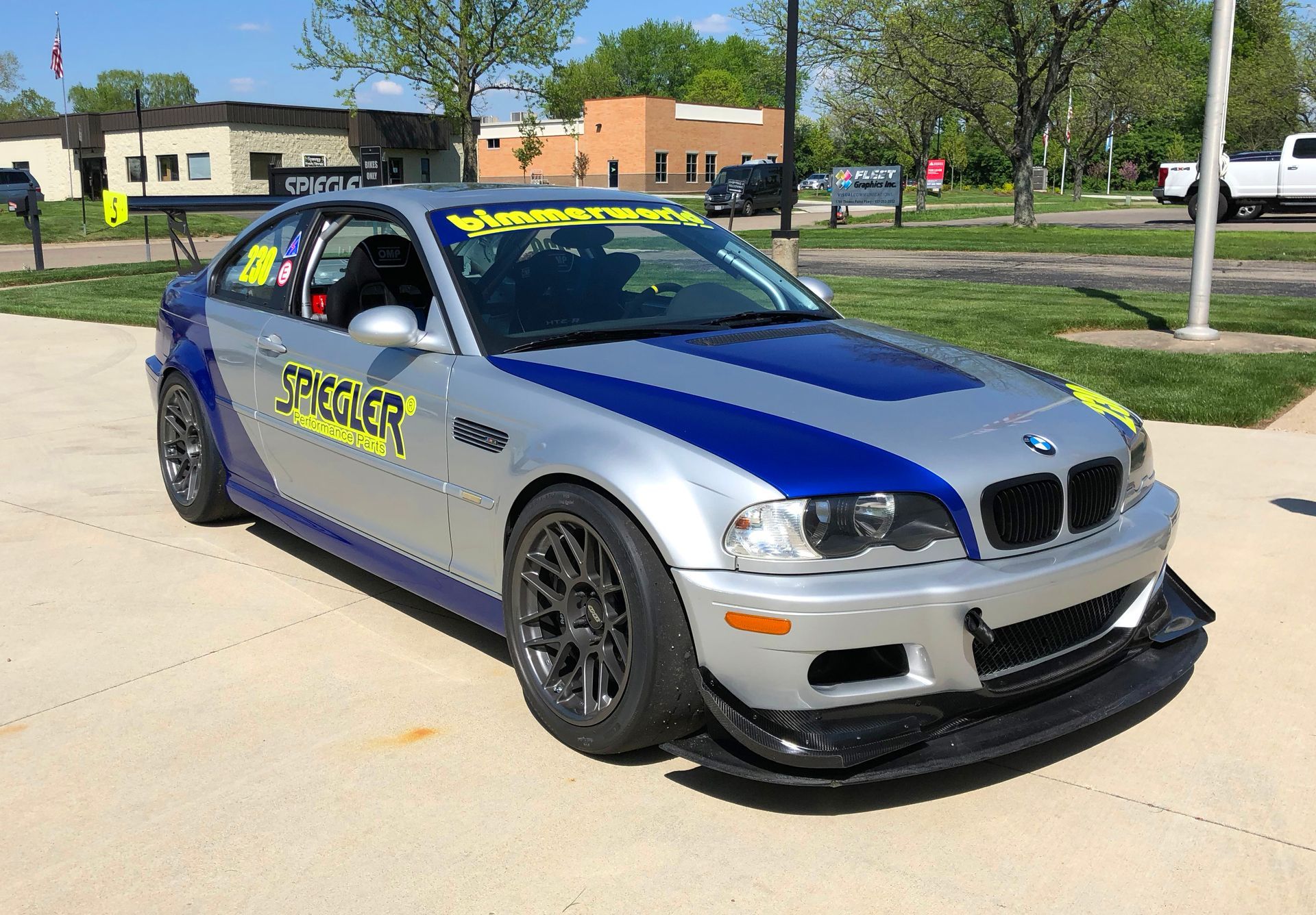 Silver and blue race car, BMW, with a wing, and a black front splitter, parked.