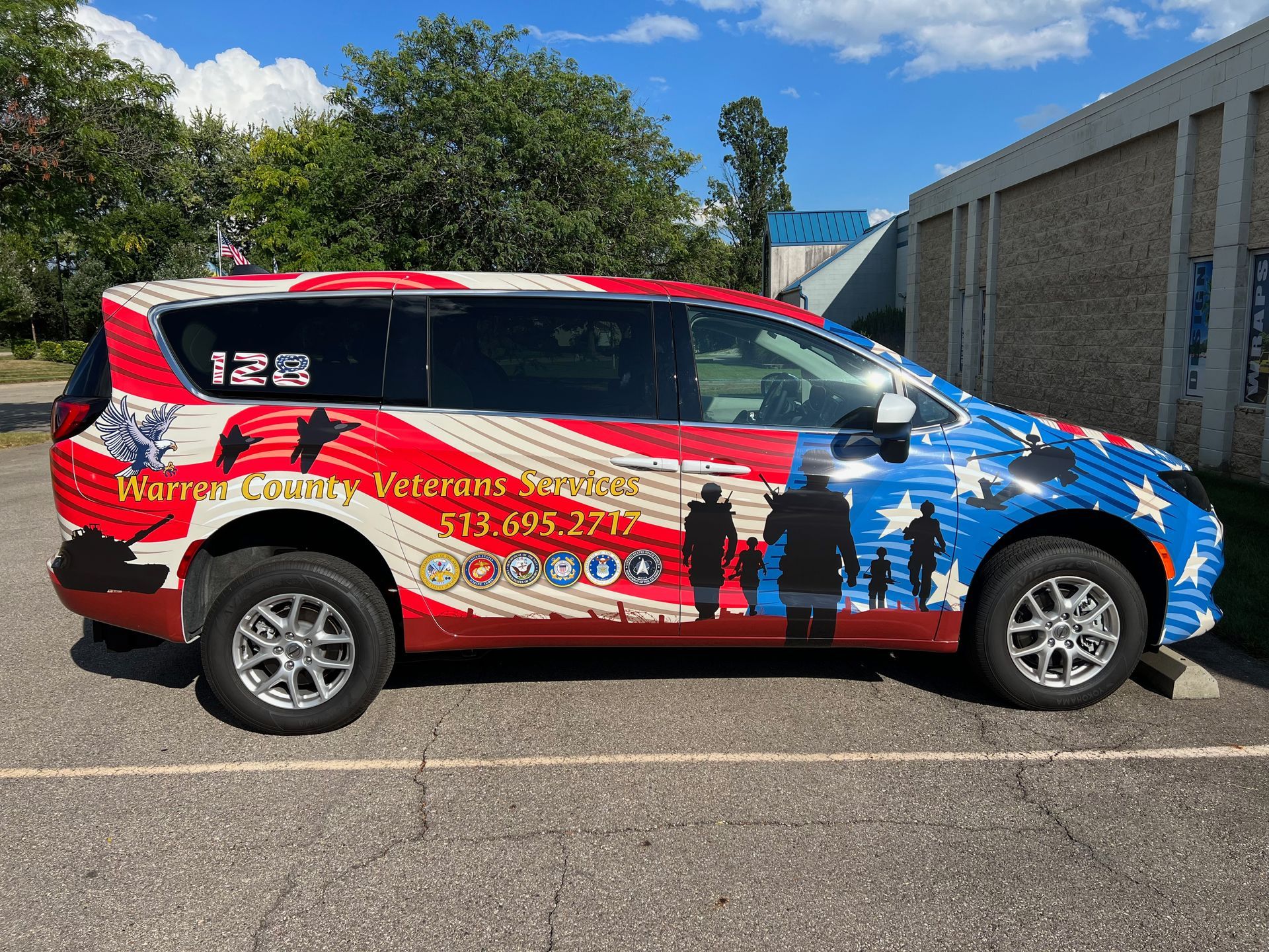 Patriotic-themed van for Warren County Veterans Services with U.S. flag design, parked near a building.