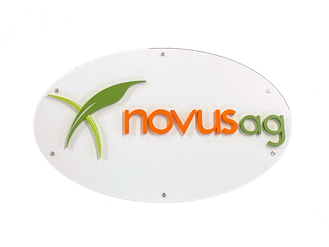Oval sign for Novus Ag, white with orange and green text and logo; agricultural business.