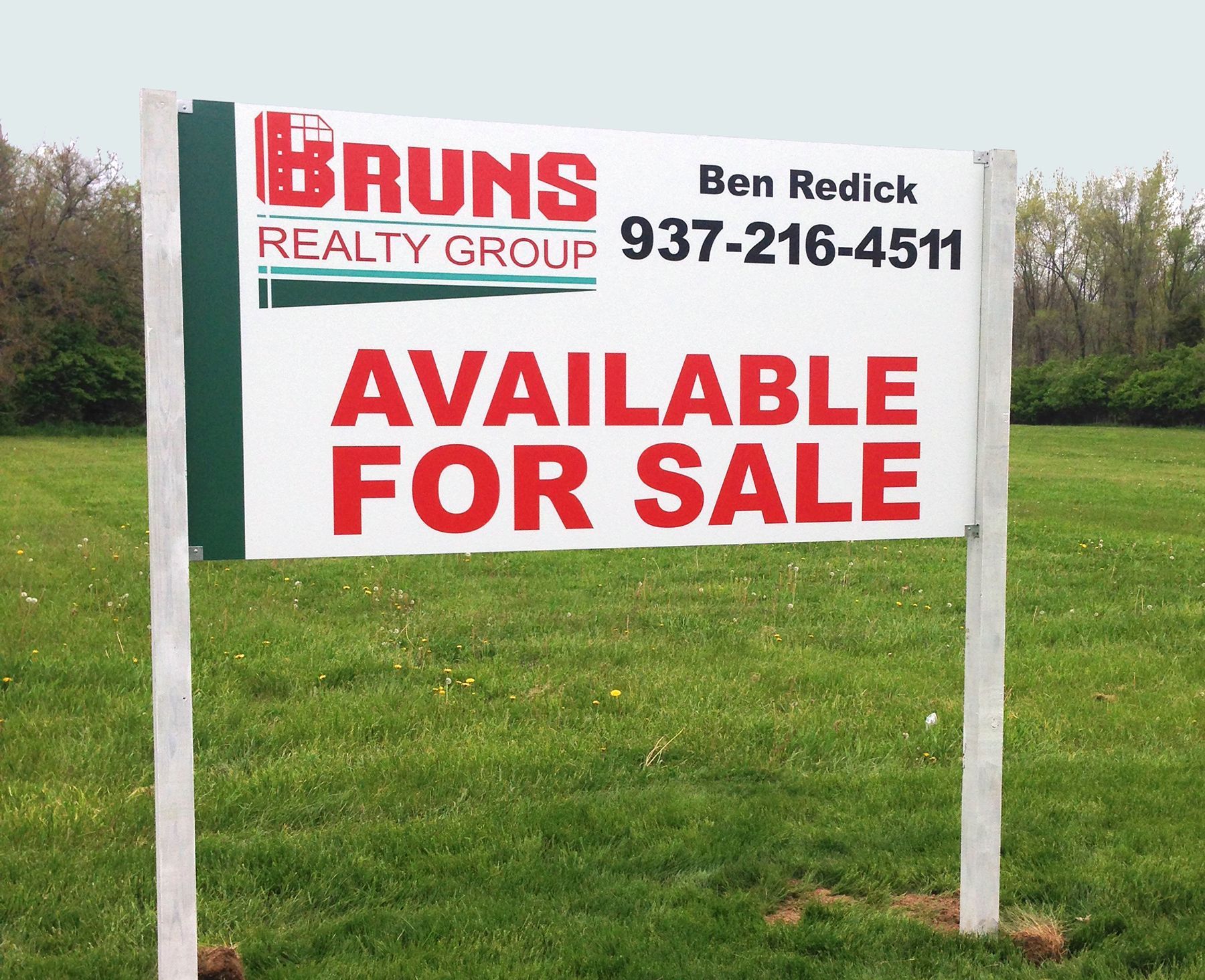 Real estate sign in a grassy field: 