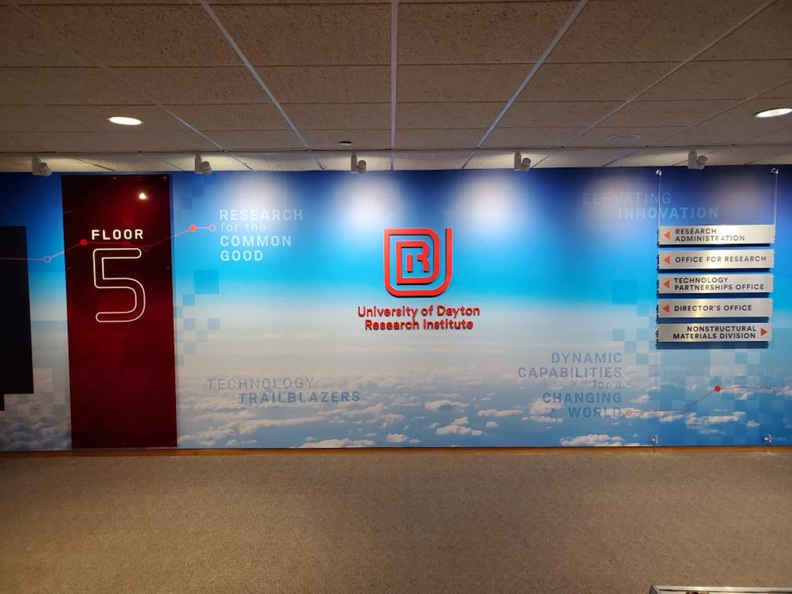 Floor 5 entrance at University of Dayton Research Institute. Blue sky background with logo and signs.