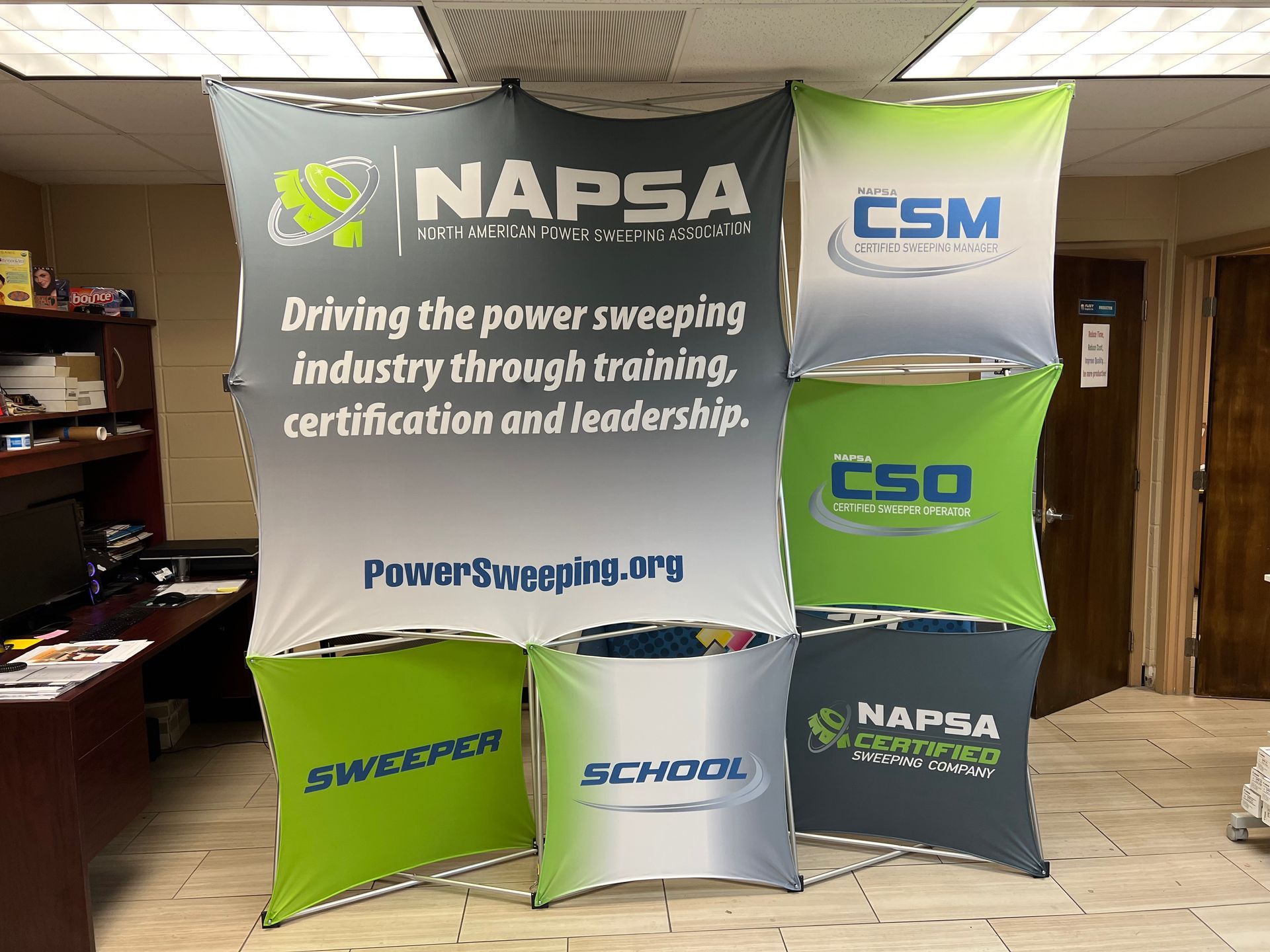 Multi-panel display with NAPSA logo and promotional text, in a room setting.
