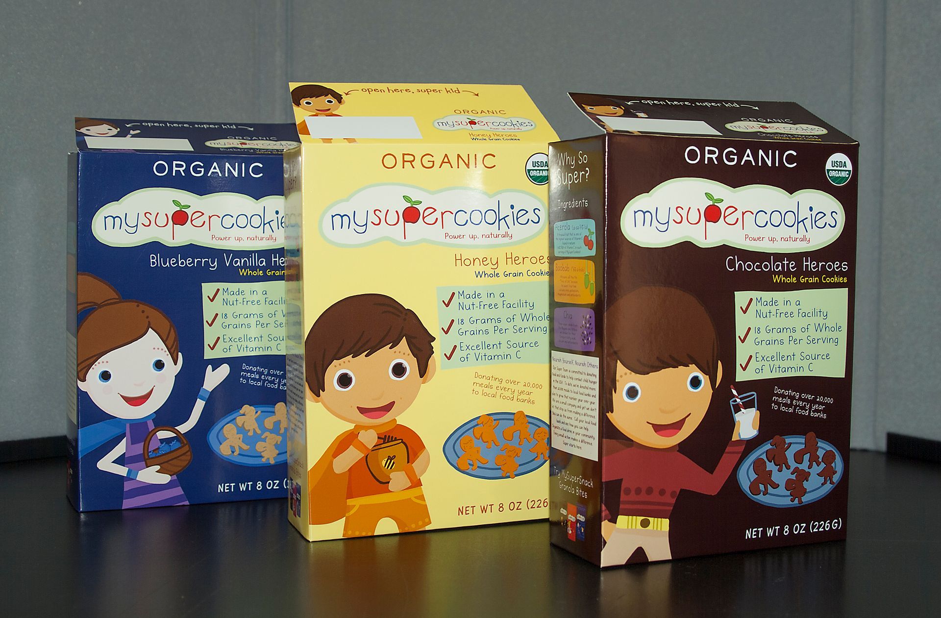 Three boxes of organic kids' snacks featuring cartoon characters, displayed on a dark surface.