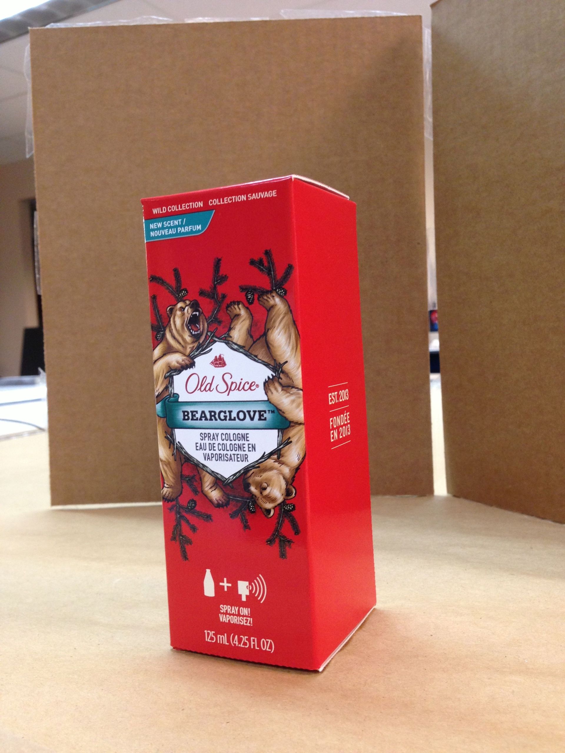 Red Old Spice Bearglove box on a table with two cardboard sheets in the background.