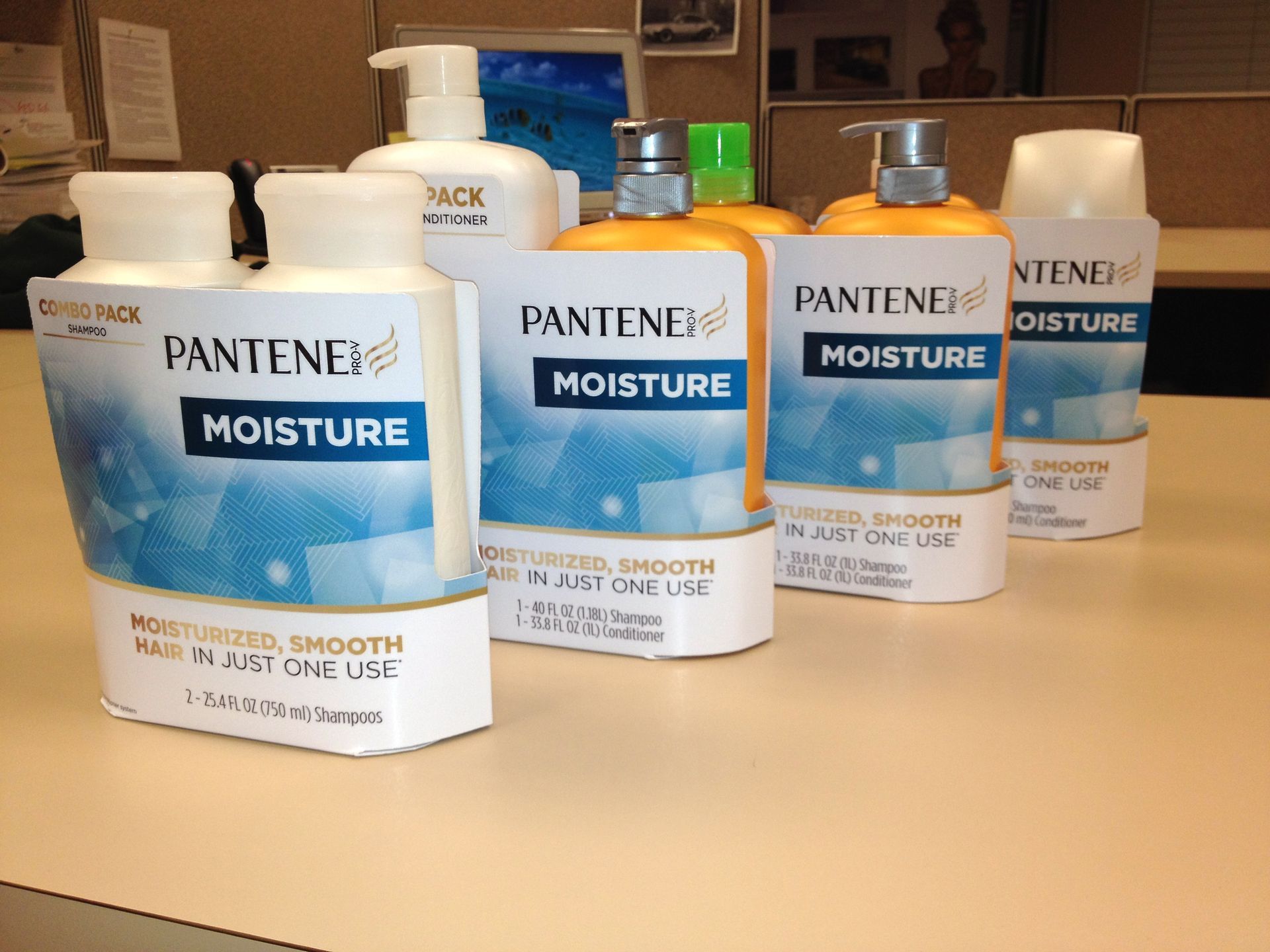Various Pantene Moisture shampoo and conditioner bottles on a desk, with light blue and white labels.