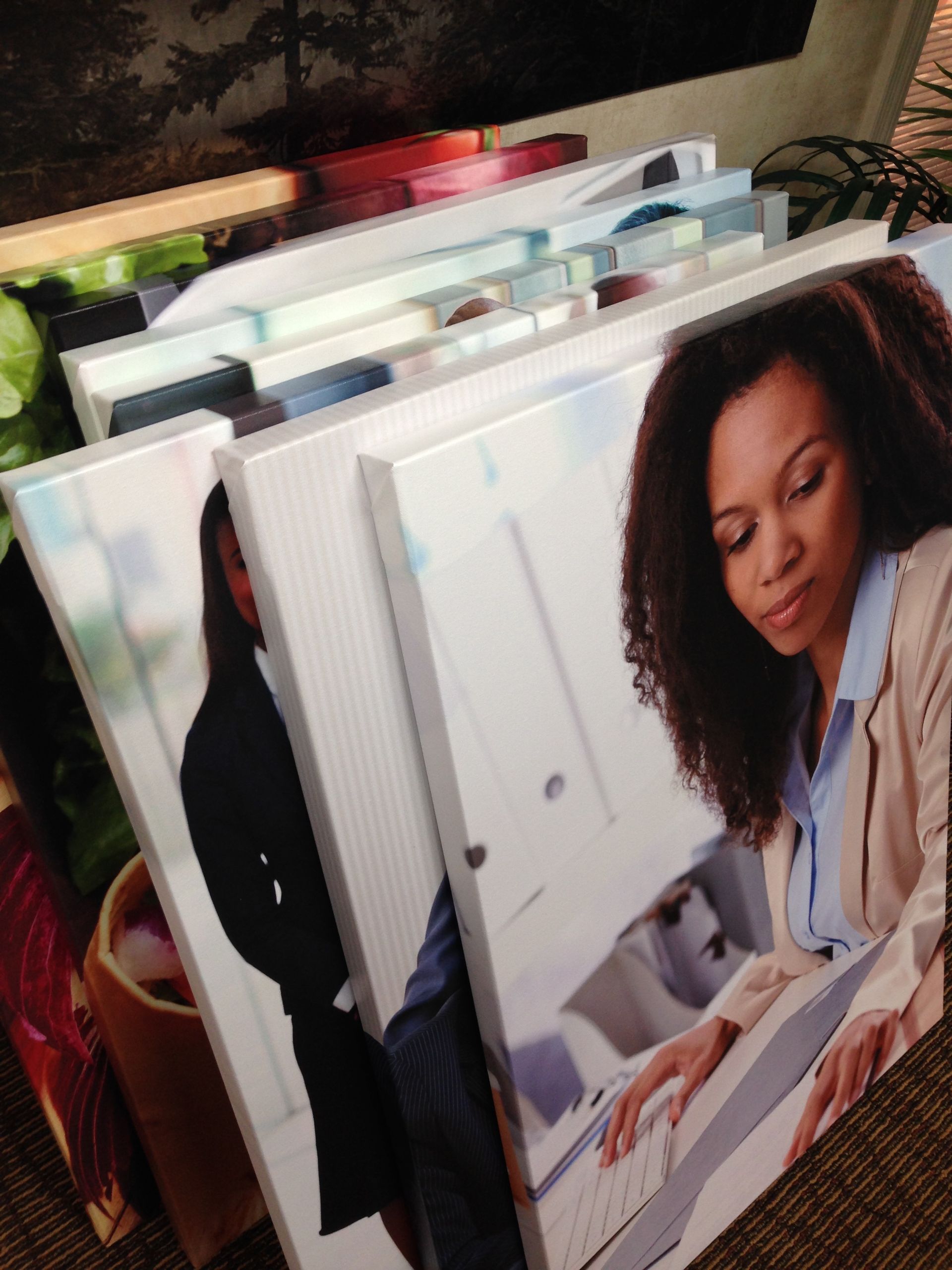 Stack of canvas prints featuring people and colorful nature scenes.