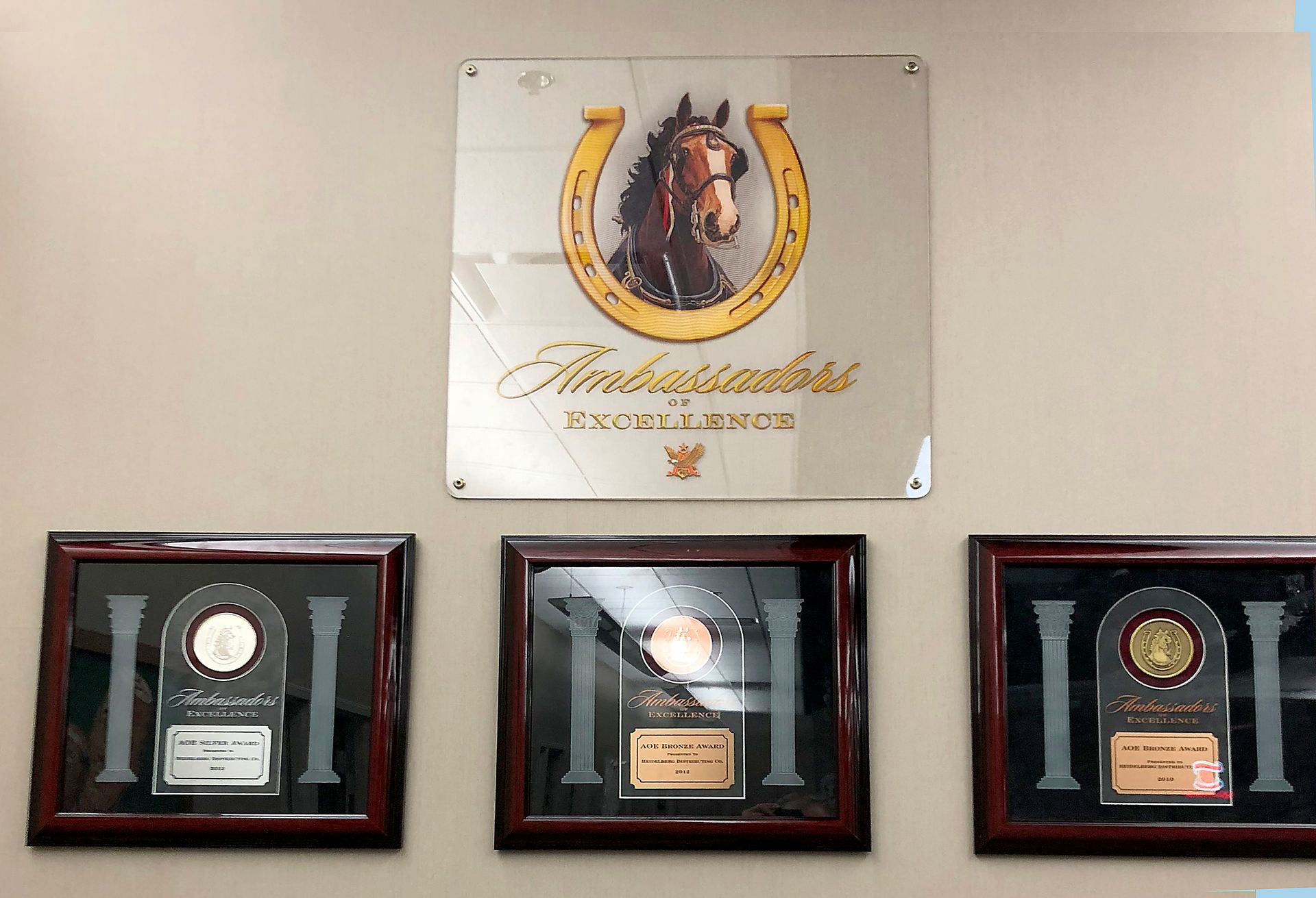 Horse logo above framed awards on a wall.
