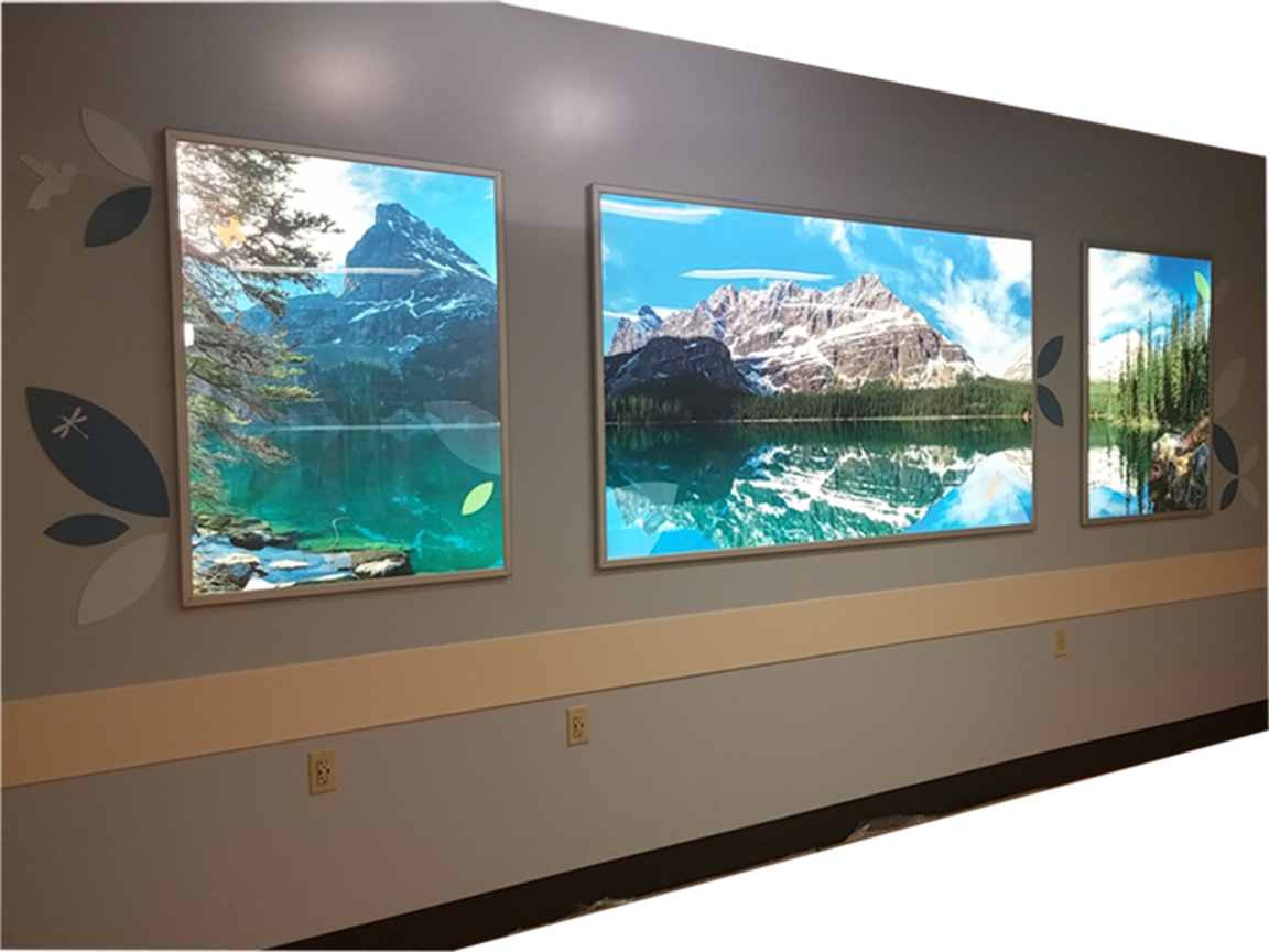 Three landscape photos of mountains and lakes on a gray wall in a hallway.