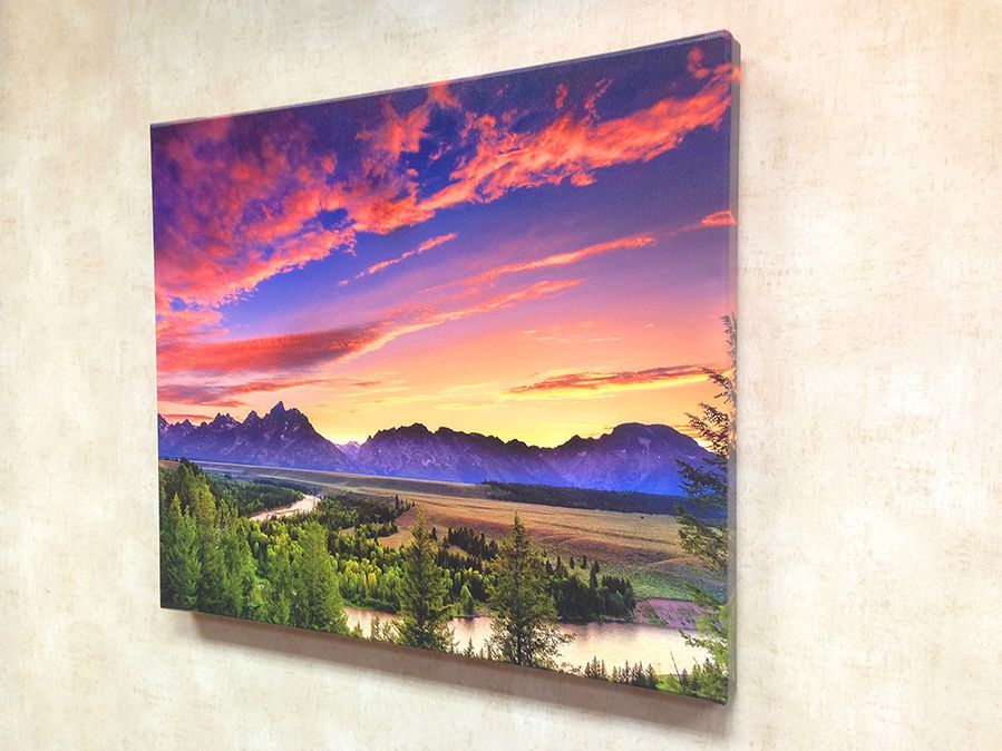 Sunset over mountains and river, canvas art on a wall. Vibrant colors: pink, orange, blue, green.