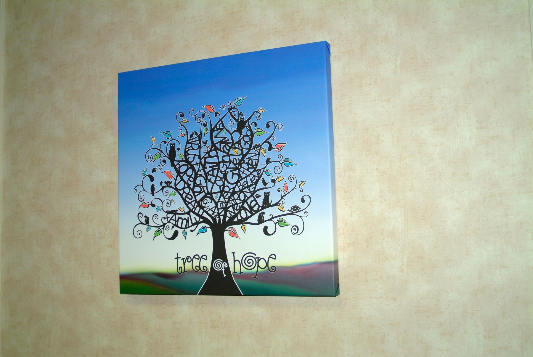 Painting of a tree with colorful birds against a blue and green gradient background. The painting hangs on a tan wall.