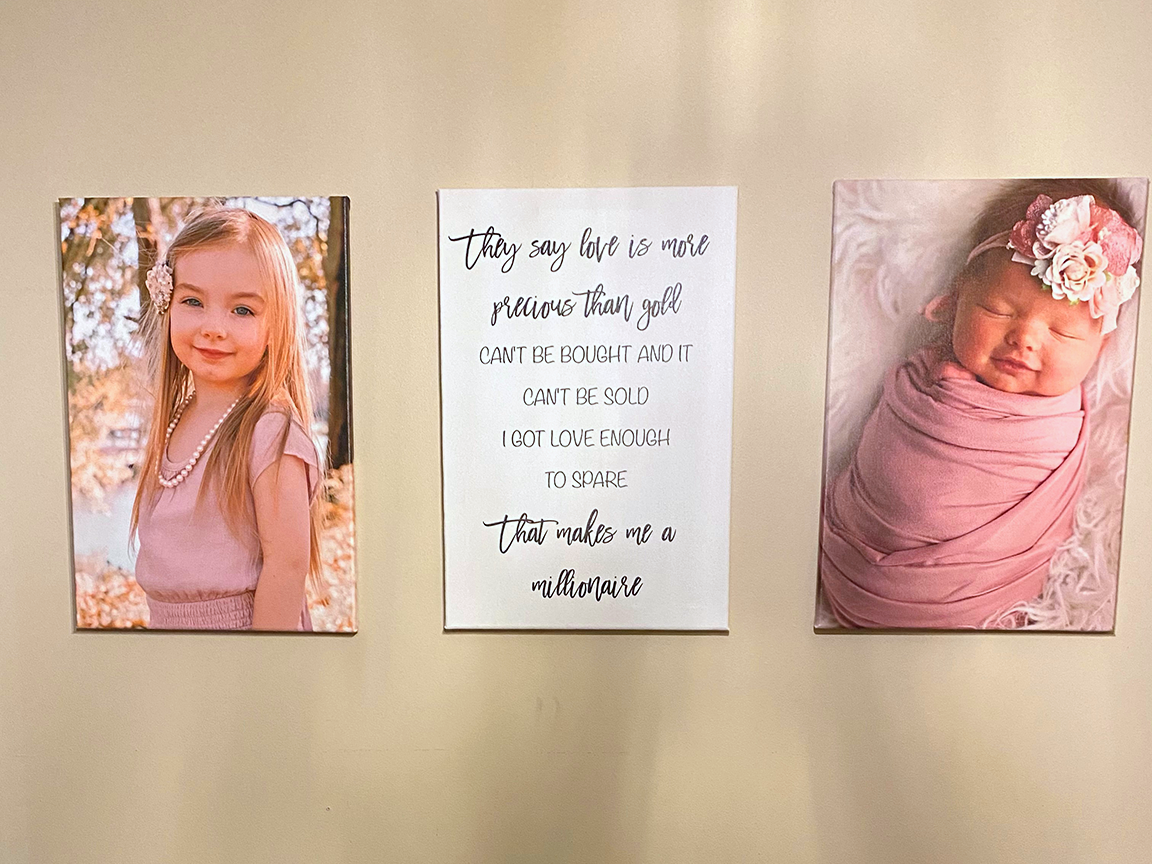 Three framed wall art pieces: a young girl, a poem, and a newborn baby. The pieces are in pink and white.