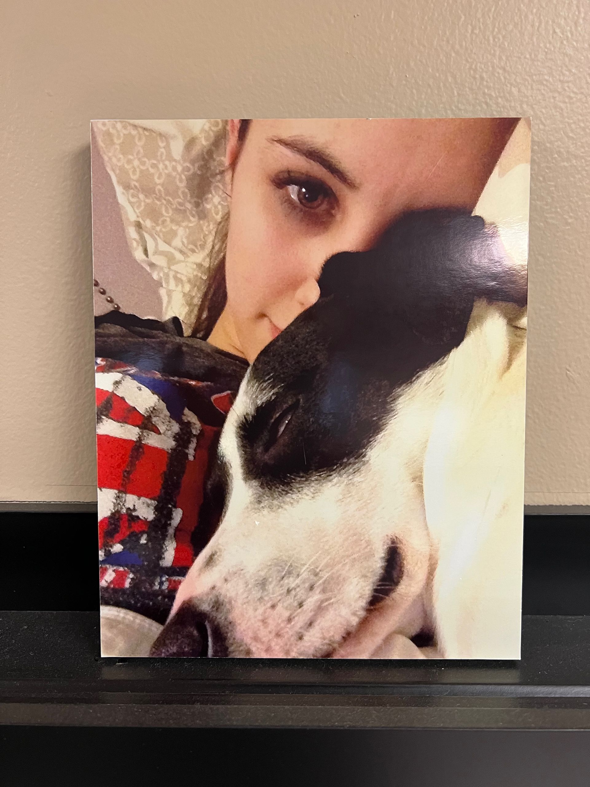 Woman snuggles a black and white dog, both looking at the viewer.