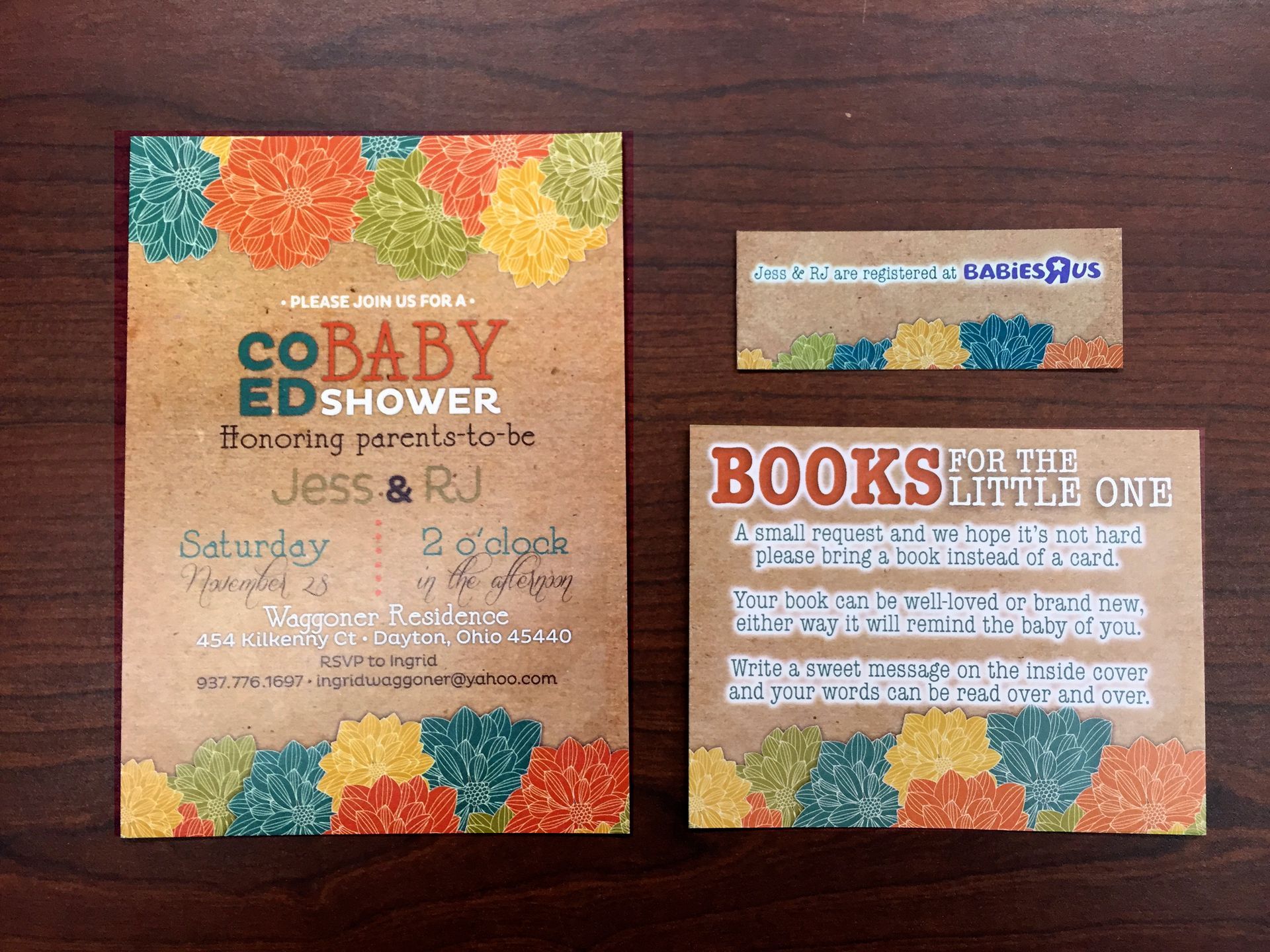 Baby shower invitations and signs on brown paper with colorful floral designs.