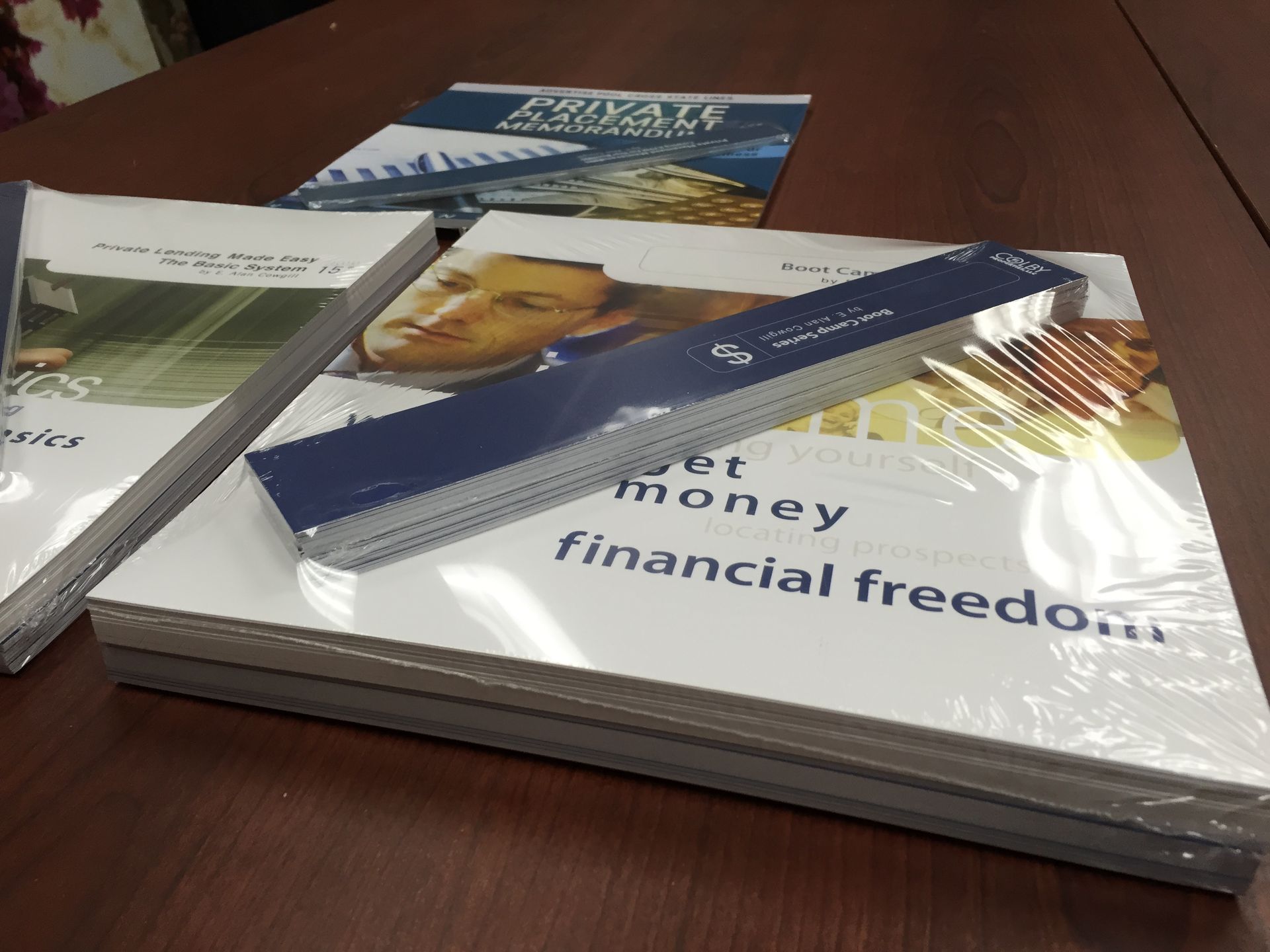 Books stacked on a table, wrapped in plastic. One says 