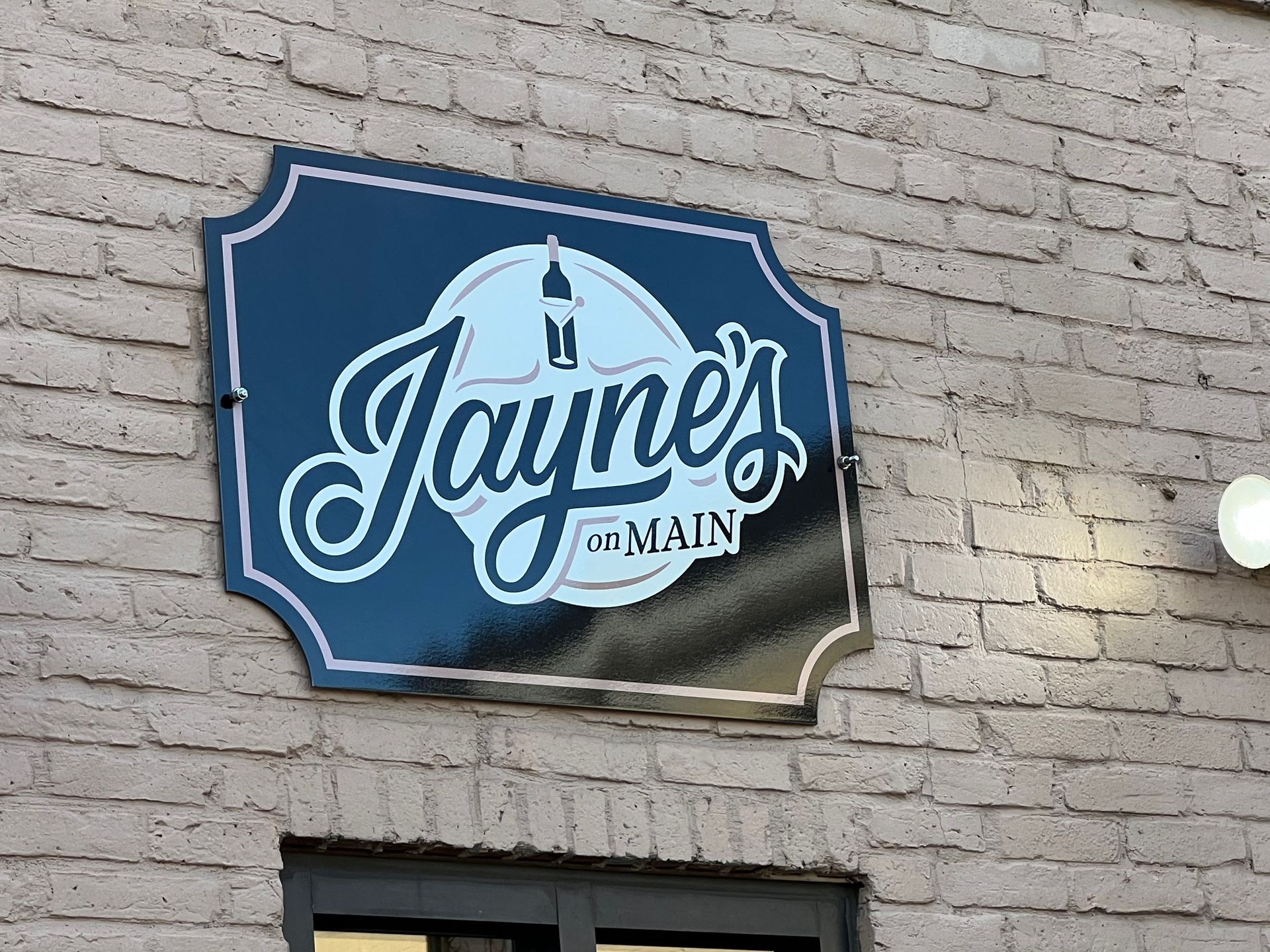 Jayne's au Main sign on a brick building. Black with white lettering and a candle logo.
