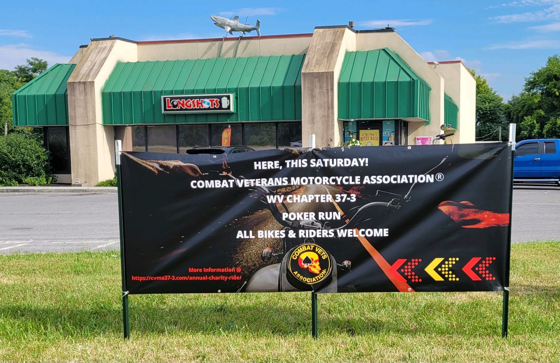 Banner for a Combat Veterans Motorcycle Association poker run; black background, green building behind it.