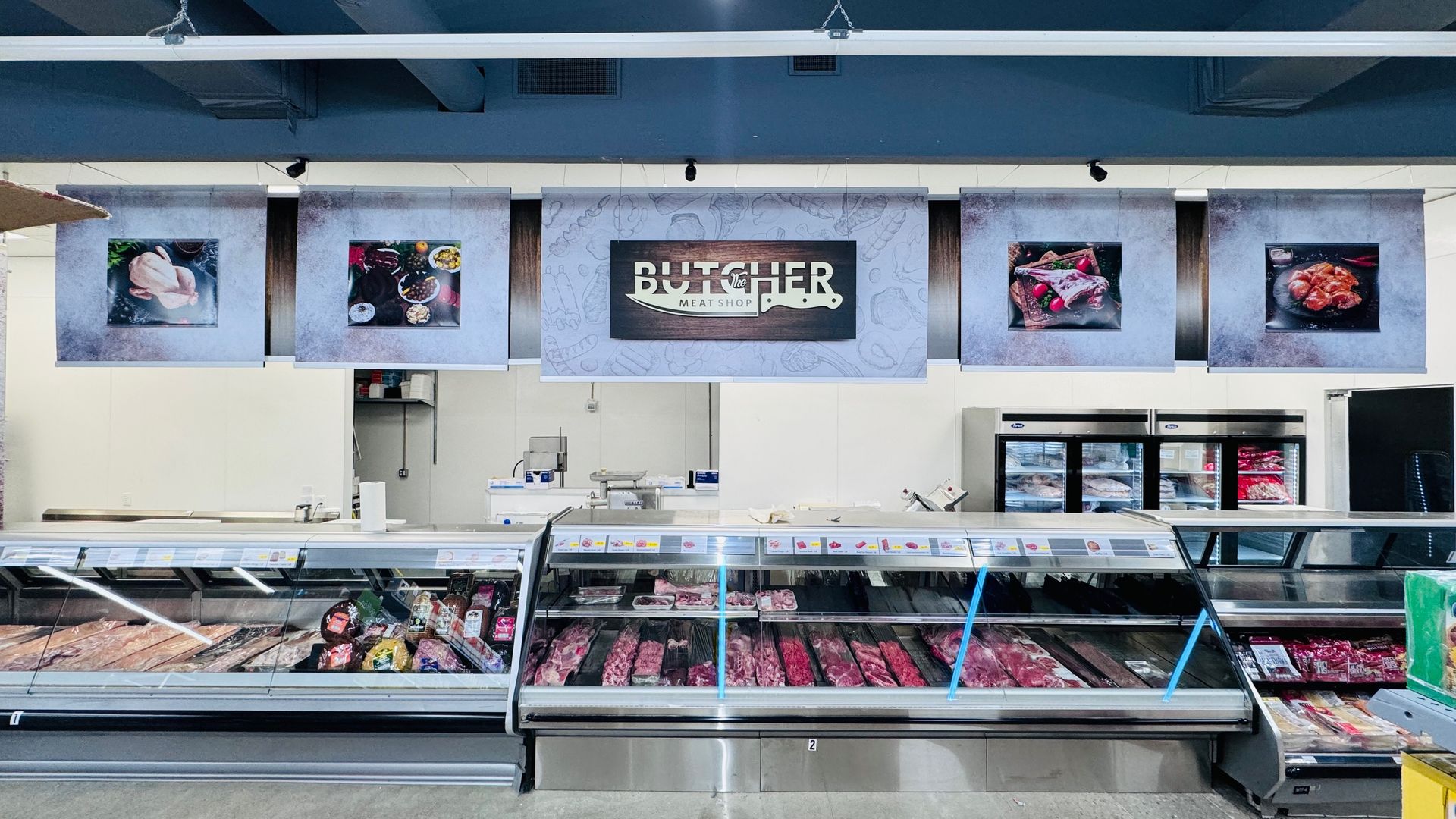 Butcher shop interior: Meat display cases under signs with meat photos and