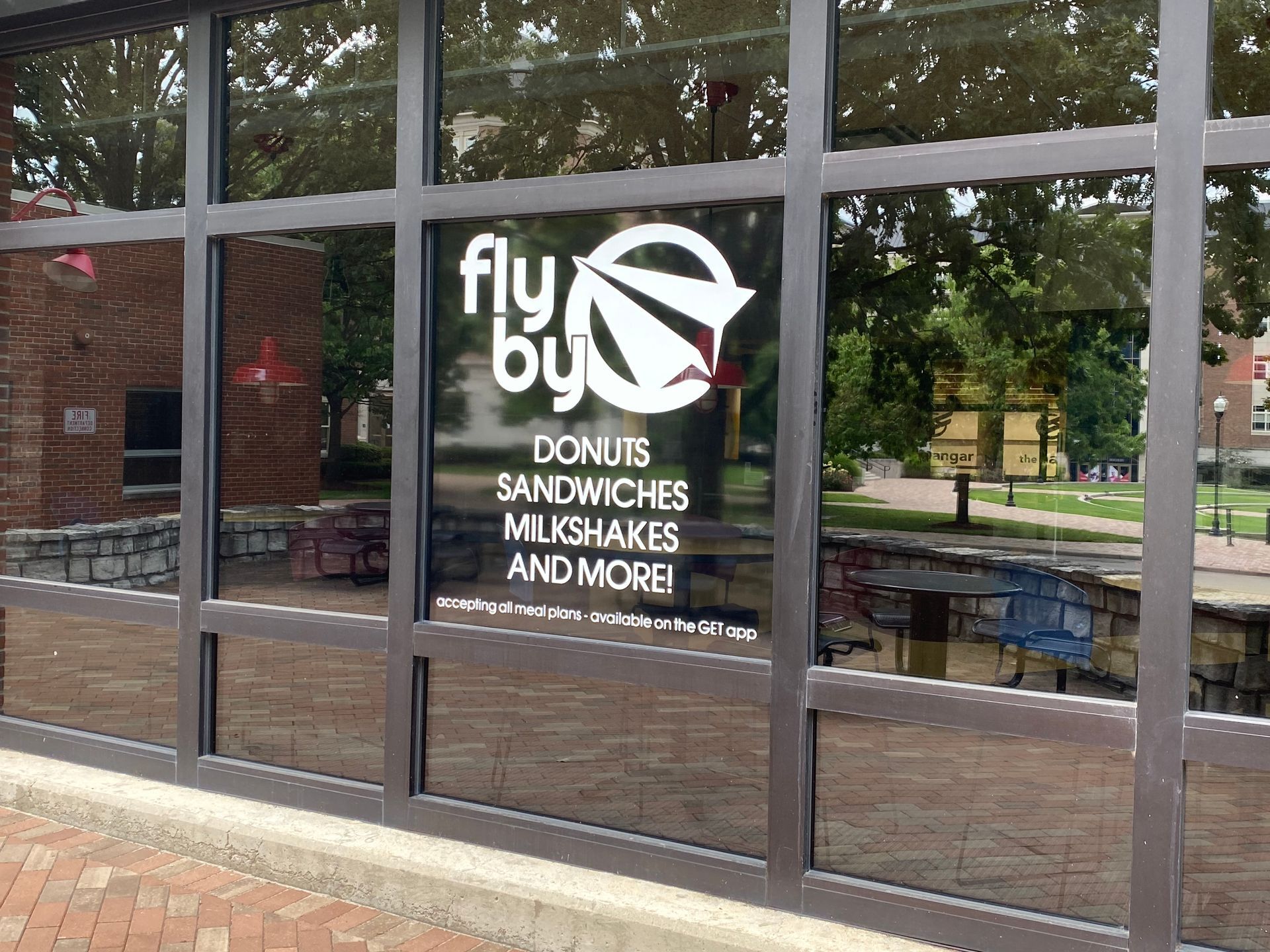 Fly By Donuts storefront with a logo of a paper airplane, in a glass window.