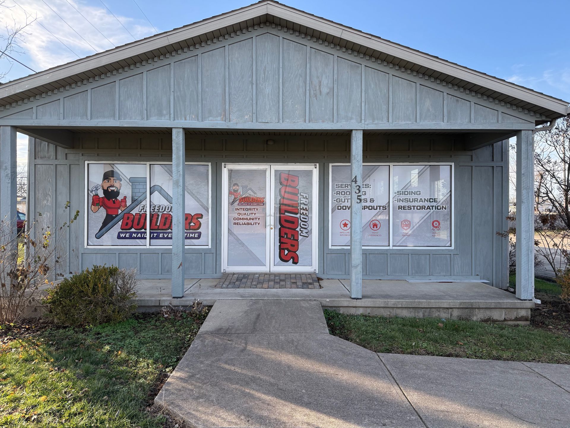 Blue building with a porch and glass doors, business sign reads