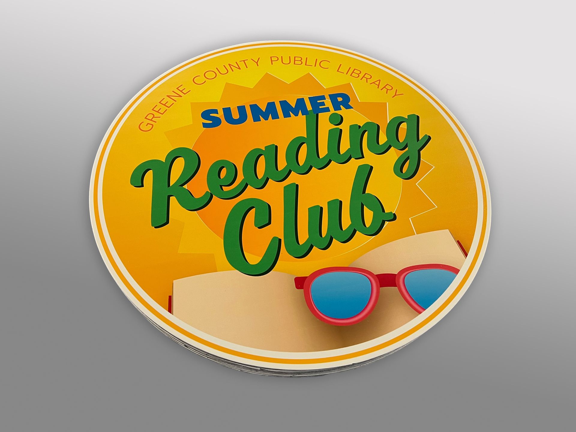 Greene County Public Library Summer Reading Club button, sun, glasses, and text on yellow background.