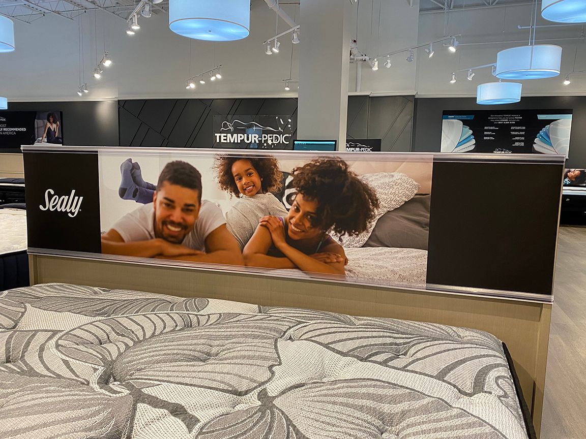 Mattress display in a store with a banner showing a happy family lying on a bed.