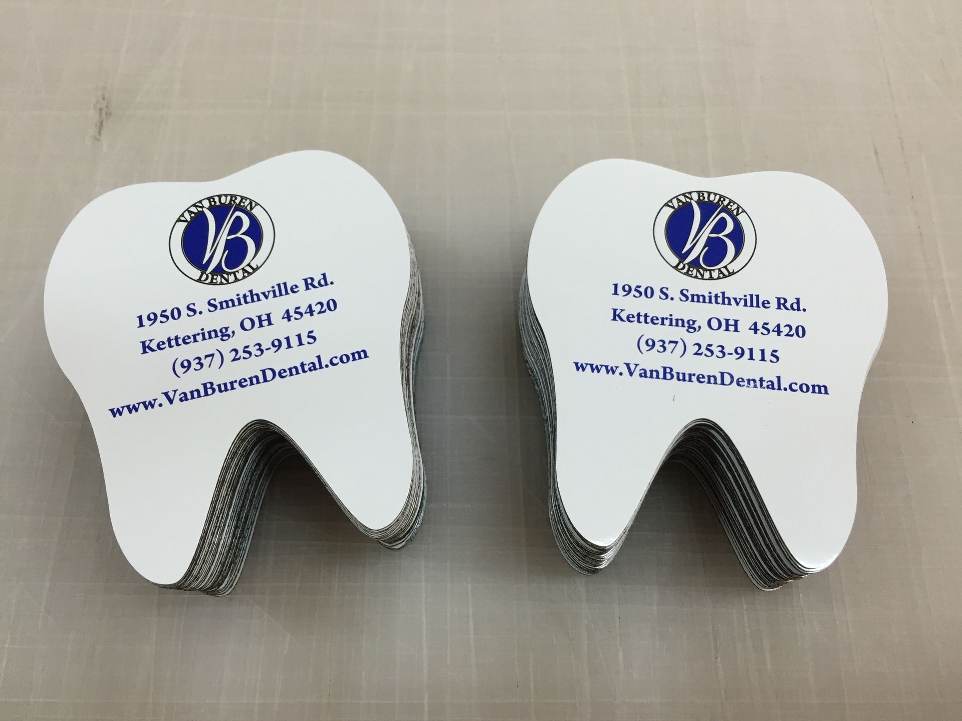 Two stacks of tooth-shaped business cards from VanBurton Dental, with logo and contact information.