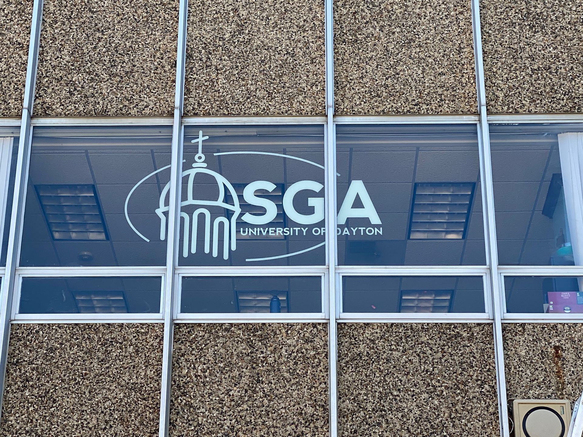 Window with SGA logo, University of Dayton, on a building exterior.
