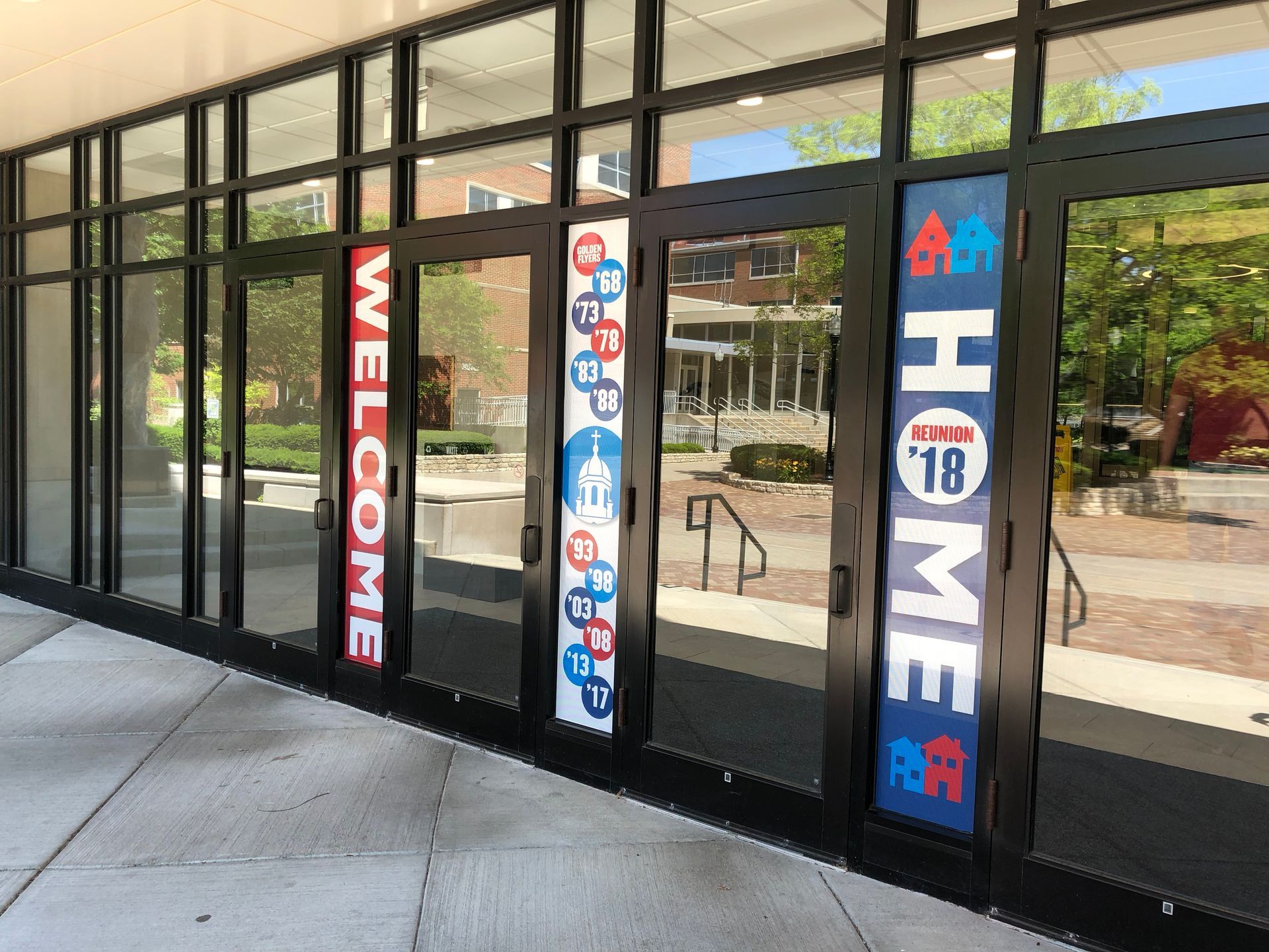 Glass doors with WELCOME and HOME banners; outdoor setting.