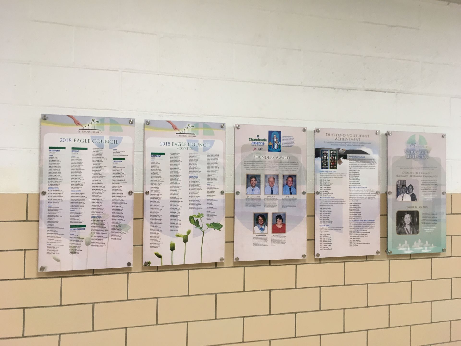 Five bulletin boards with posters, on a brick and white wall.