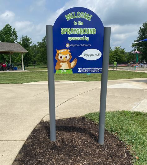 Sign for a sprayground with owl mascot; blue and green text, 