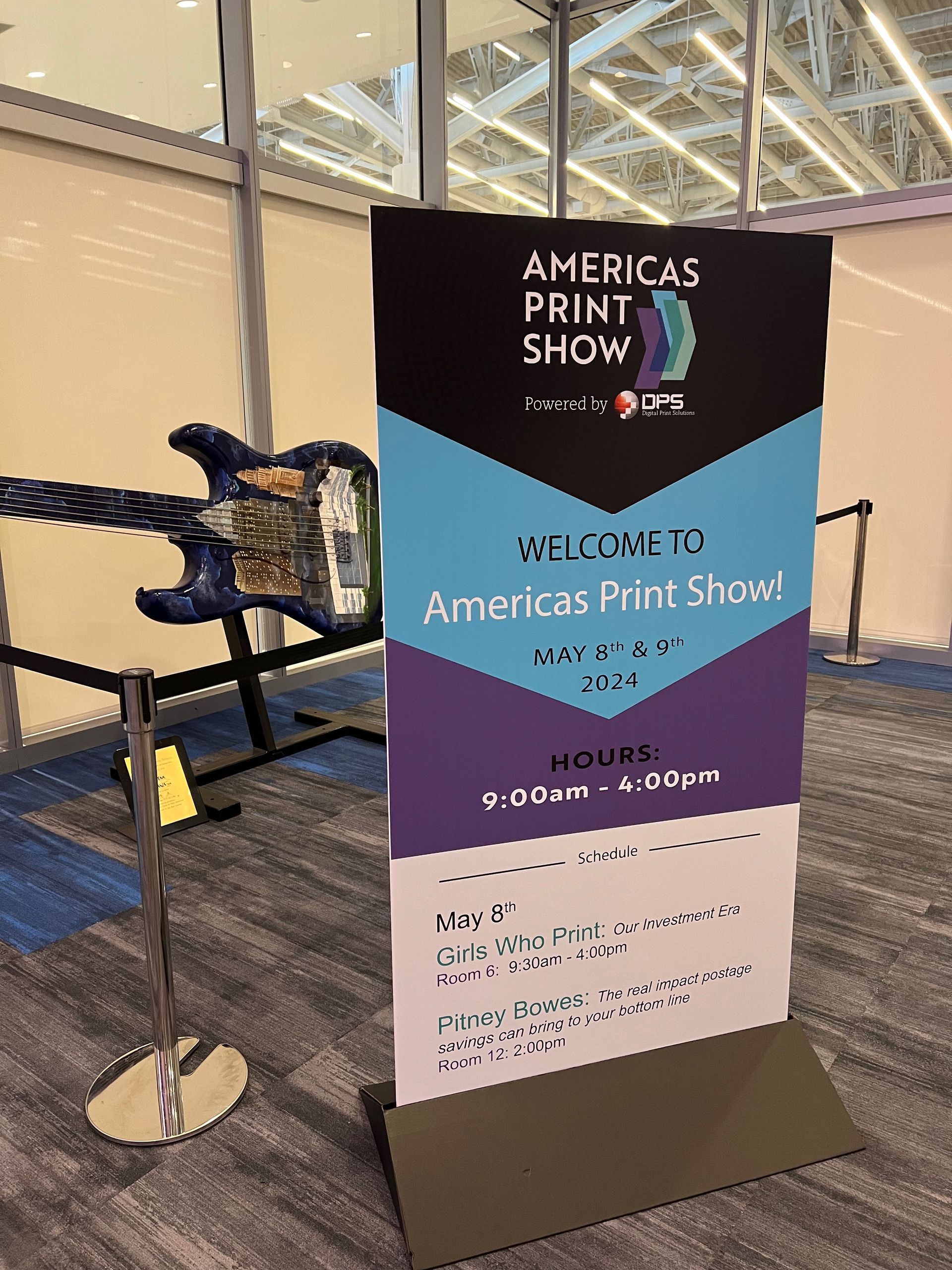 Banner for Americas Print Show in Vancouver, with event details. Features blue, purple, and black colors.