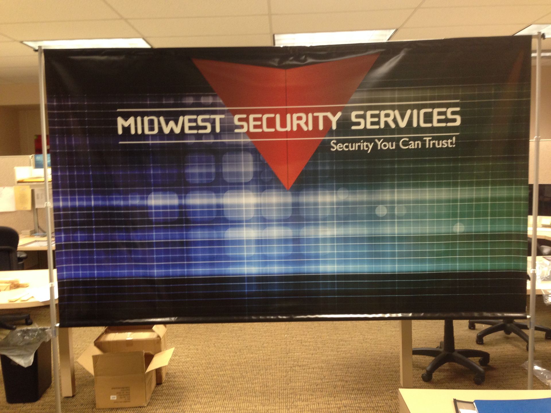 Banner for Midwest Security Services: Black background with red triangle and logo in a modern office setting.