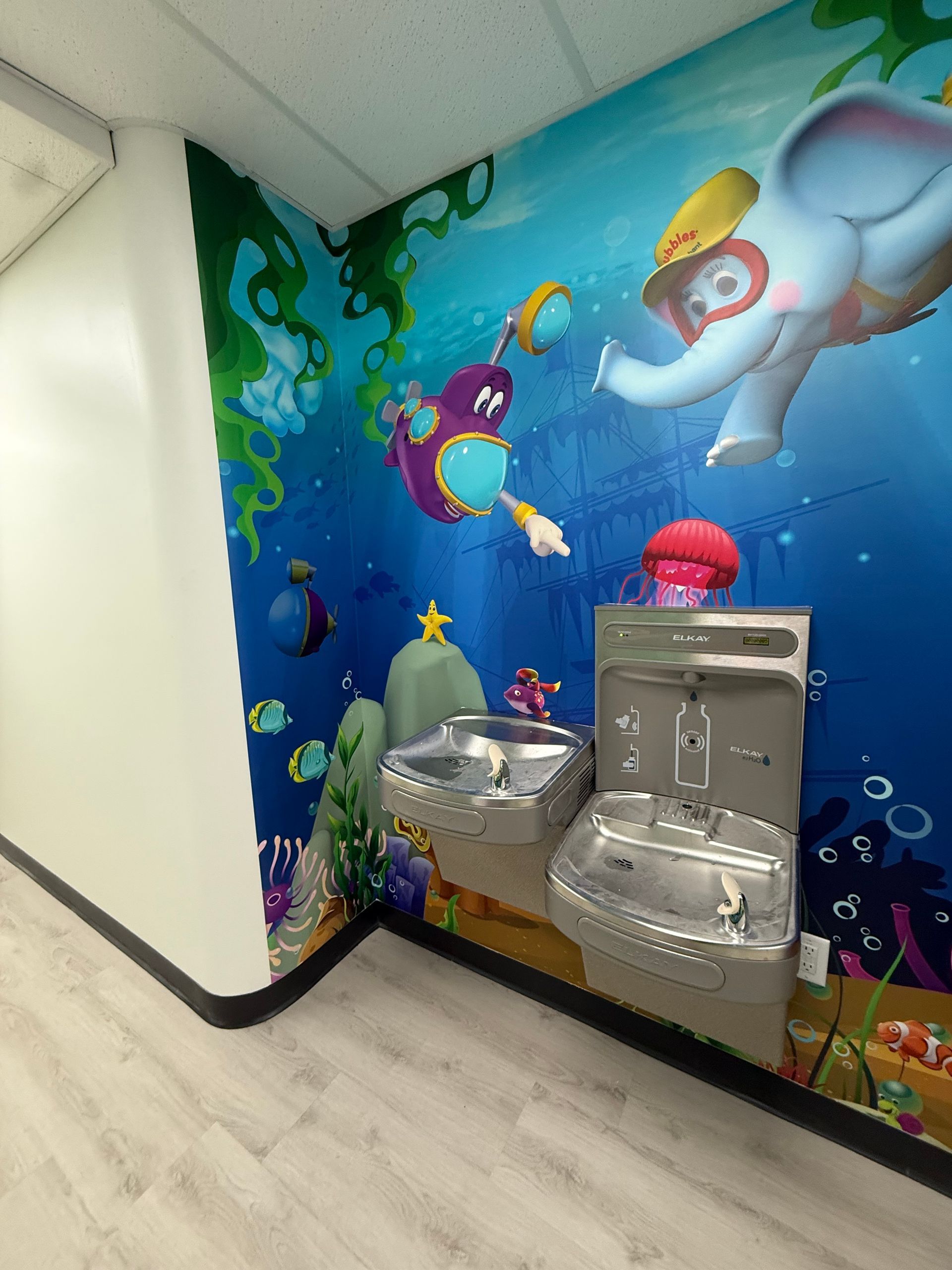 Playful underwater mural with water fountains in a brightly colored hallway.