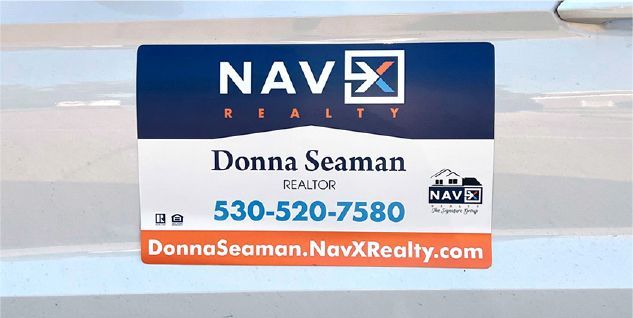 Real estate sign on a car door for Donna Seaman, NAVX Realty. Includes contact info.