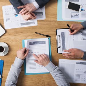 A group of people are sitting at a table looking at papers.
