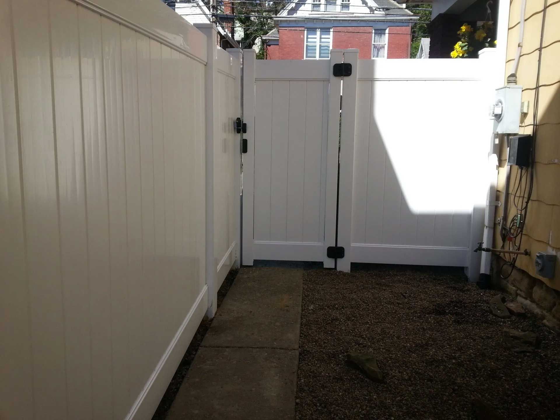 A white fence with a gate in the backyard