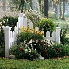 A white picket fence surrounded by flowers in a garden.