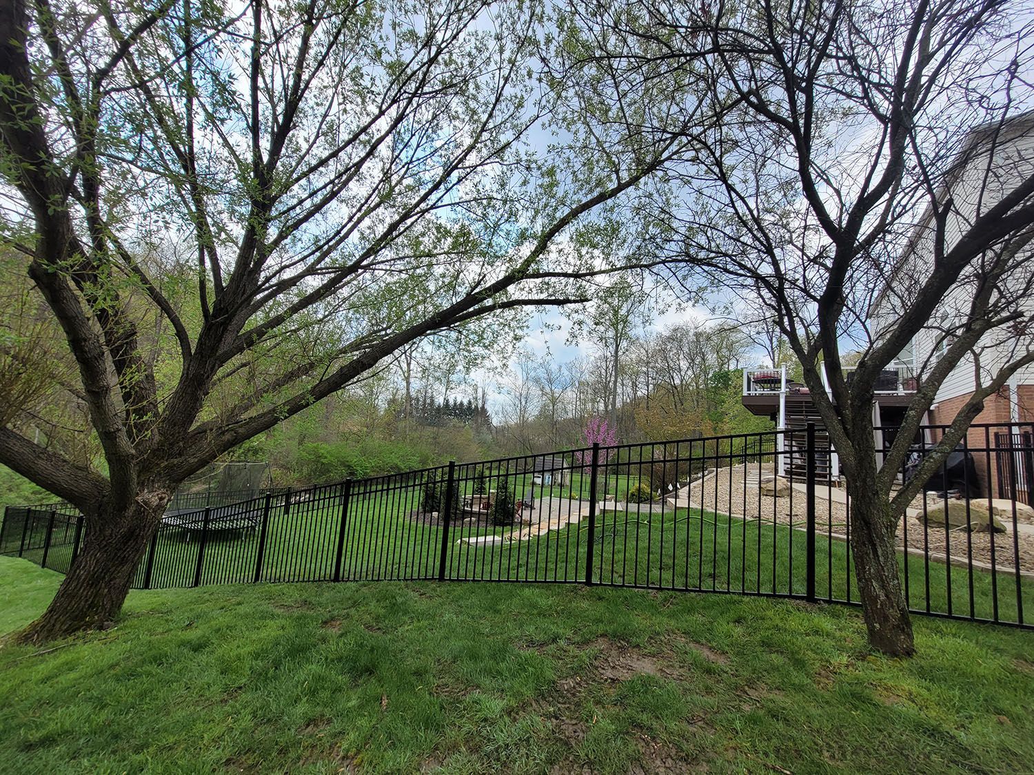 A fence with trees in the background and a house in the background.