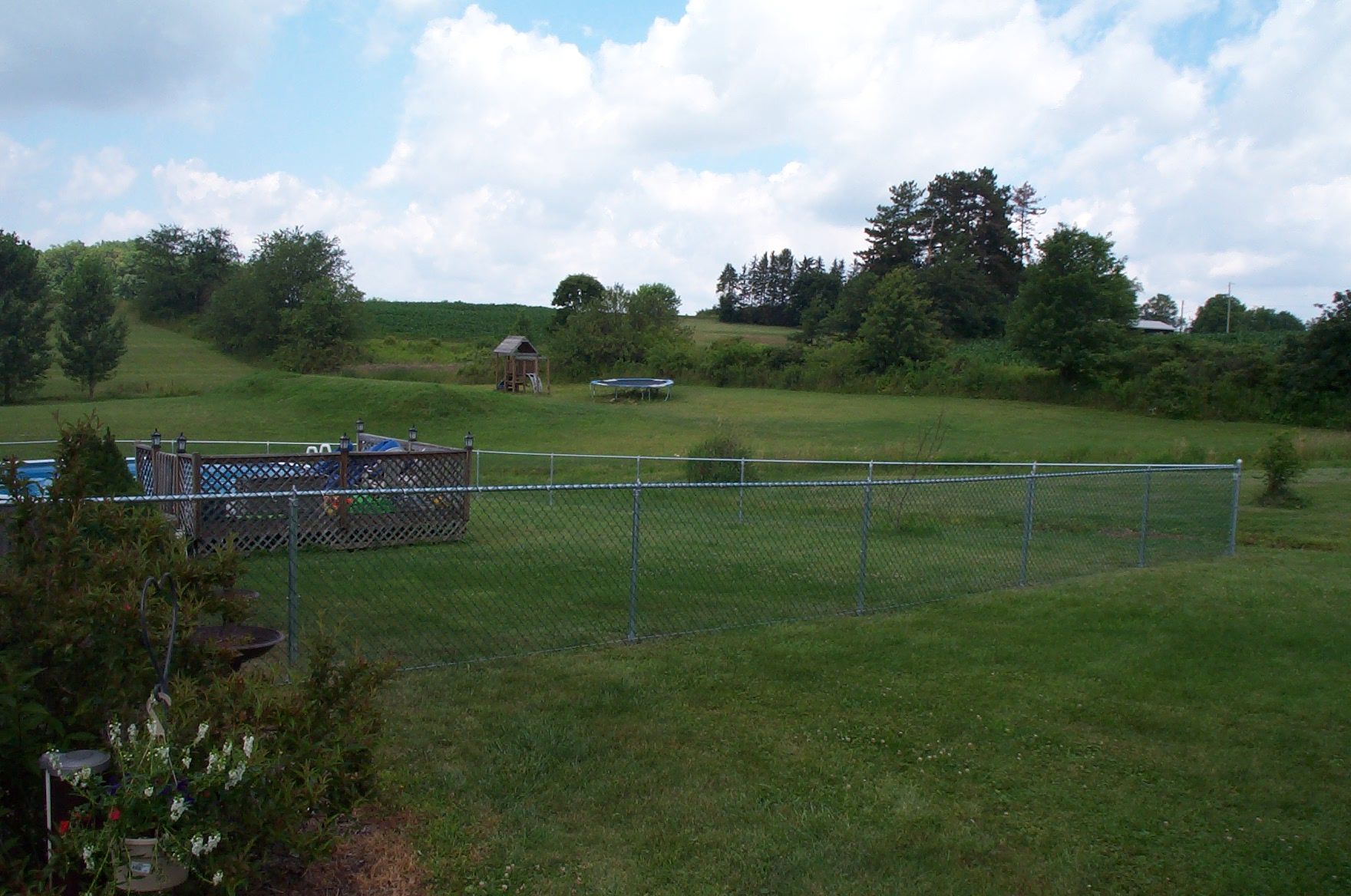 A chain link fence surrounds a large grassy field.