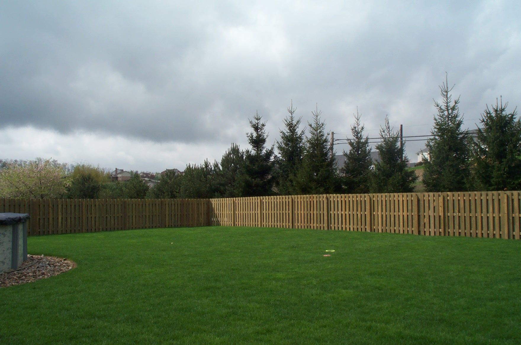 A backyard with a wooden fence and trees in the background