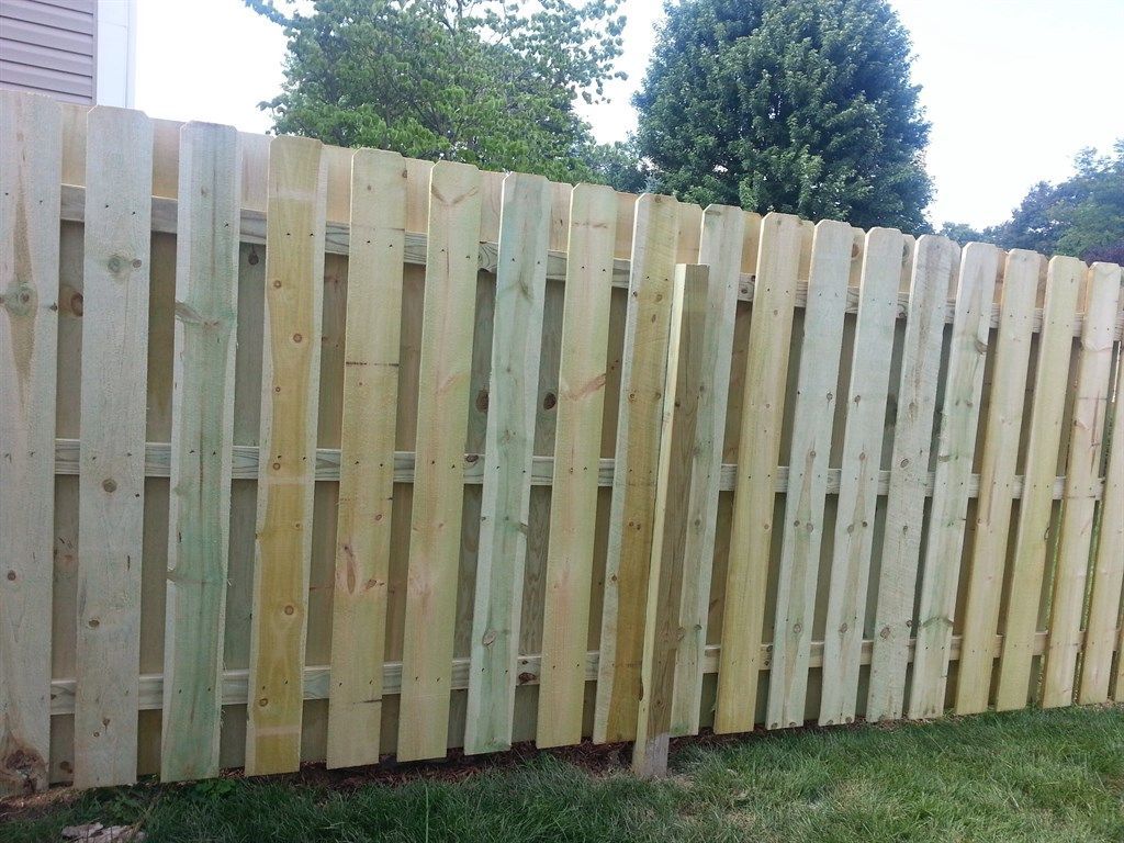 A wooden fence is sitting in the grass in front of a house.