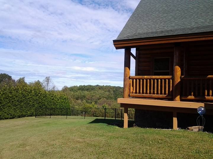 A log cabin sits in the middle of a lush green field