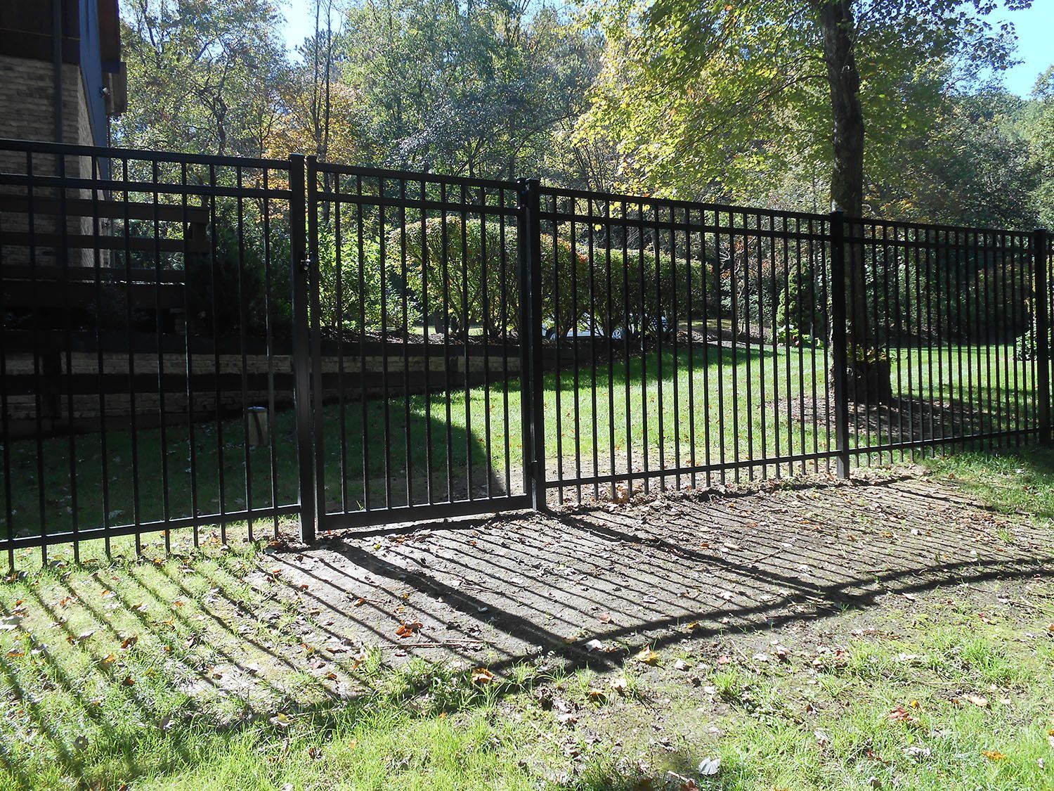 A black metal fence surrounds a lush green yard