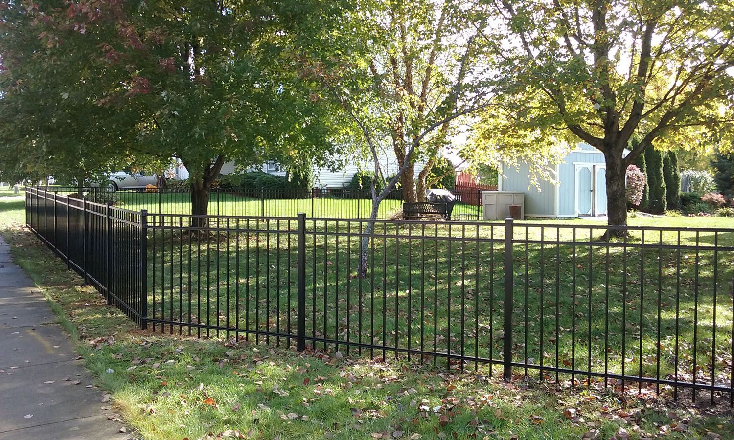 A black wrought iron fence surrounds a lush green field.