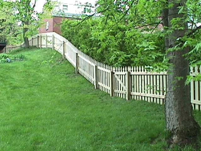 A wooden picket fence surrounds a lush green yard.