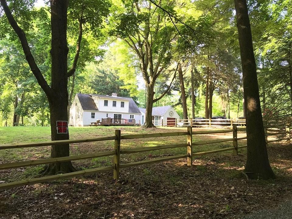 A wooden fence surrounds a house in the woods