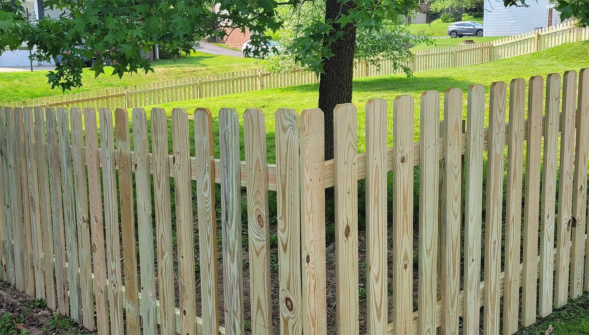 A wooden picket fence surrounds a lush green field.