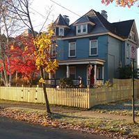 A large blue house with a yellow fence in front of it.
