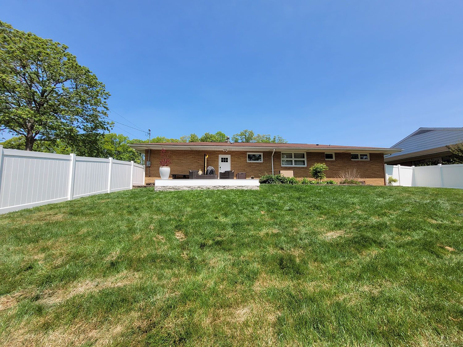 A large lawn in front of a house with a white fence.